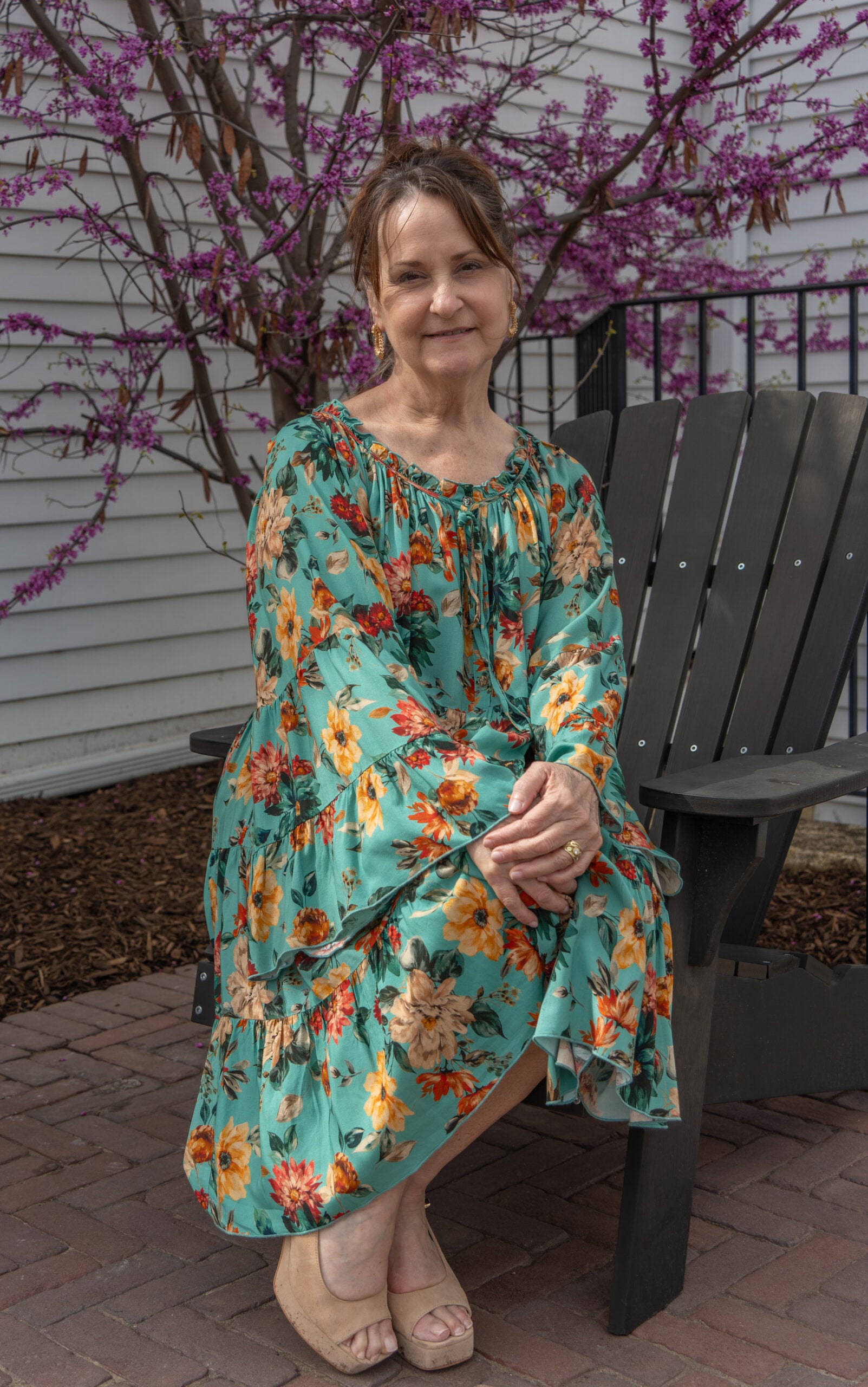 Woman in floral dress by blooming tree.