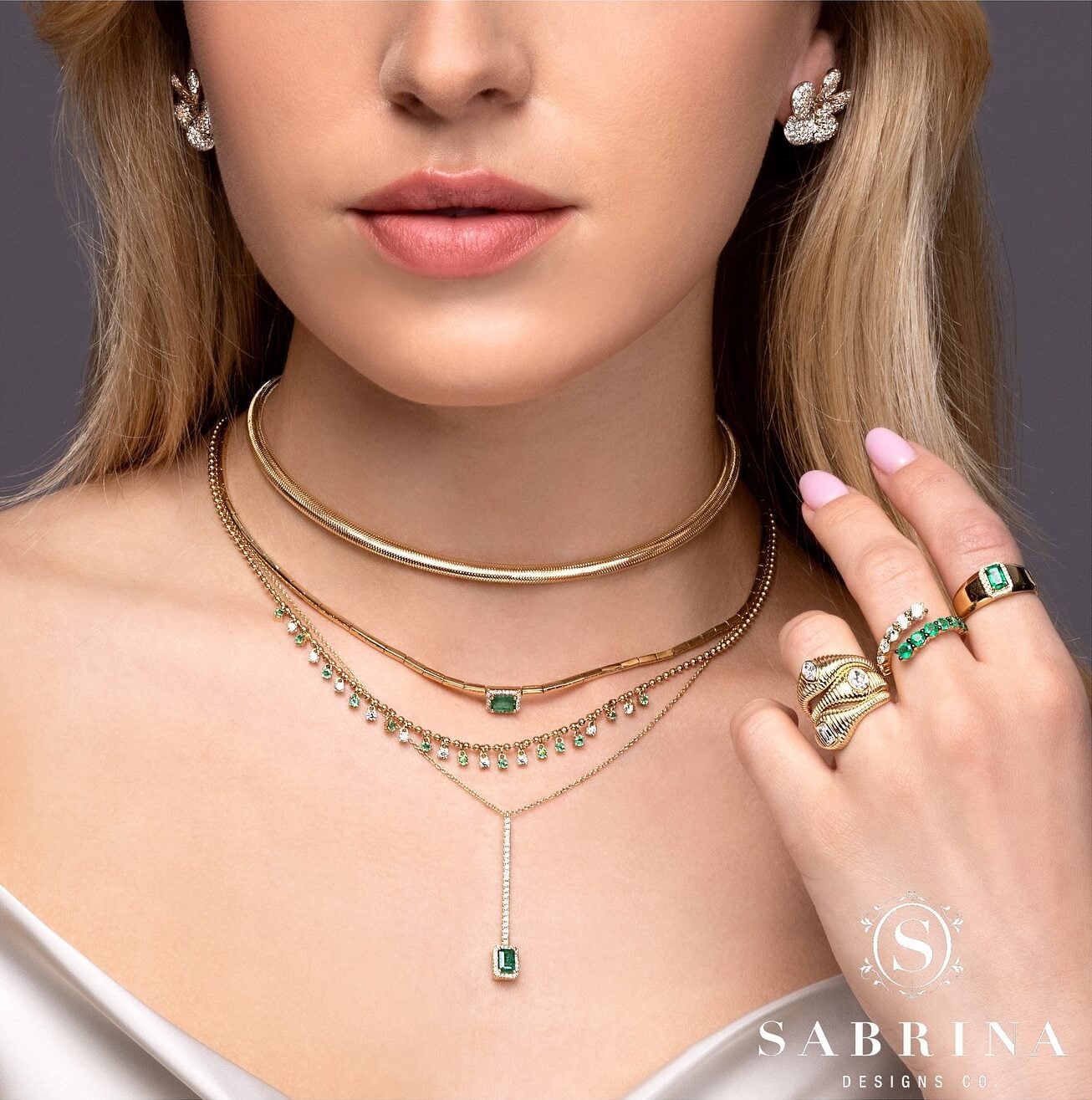 Woman wearing elegant gold and emerald jewelry.